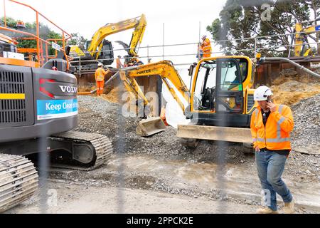 Tauranga Neuseeland - 9 2023. April; schwere Erdbewegungsmaschinen und spezialisierte Bahnarbeiter, durch Zaun. Stockfoto