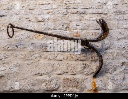 Rab, Kroatien - 24. August 2022: An einer veralteten Holzwand, einem rustikalen Gebäude, ist ein Eisenhupfer angebracht. Stockfoto