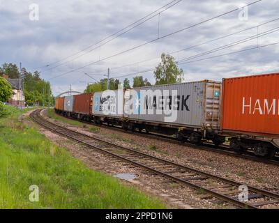 Angelsberg, Schweden - 28. Mai 2022: Ein Güterzug fährt langsam entlang der gewundenen Gleise, seine Autos sind mit Fracht und rollendem Material gefüllt. Die s Stockfoto