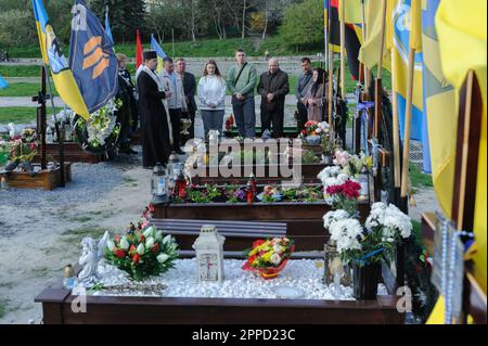 Lemberg, Ukraine 23. April 2023. Menschen stehen auf Gräbern auf dem Marsfeld des Friedhofs Lychakiv. Helden der Ukraine, Soldaten, die das Territorium der Ukraine verteidigten, sind hier begraben. Russland marschierte am 24. Februar 2022 in die Ukraine ein und löste damit den größten militärischen Angriff in Europa seit dem Zweiten Weltkrieg aus Stockfoto