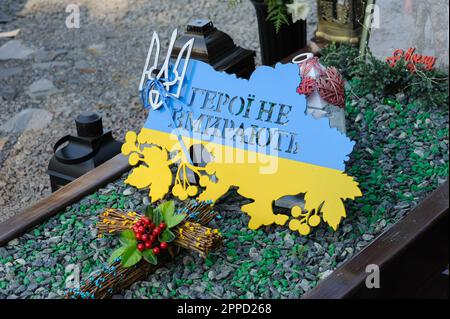 Lemberg, Ukraine 23. April 2023. Ein Schild mit der Inschrift „Helden sterben nicht“ in Form einer Karte der Ukraine und den Farben der Flagge, die auf dem Grab eines gefallenen Soldatengrabes auf dem Marsfeld des Friedhofs Lychakiv zu sehen sind. Helden der Ukraine, Soldaten, die das Territorium der Ukraine verteidigten, sind hier begraben. Russland marschierte am 24. Februar 2022 in die Ukraine ein und löste damit den größten militärischen Angriff in Europa seit dem Zweiten Weltkrieg aus Stockfoto