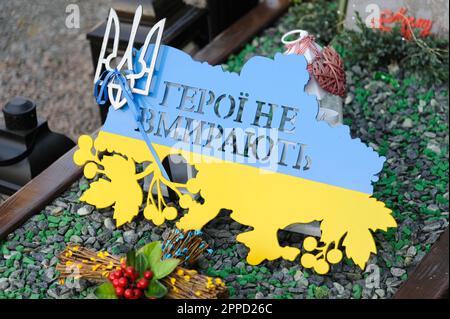 Lemberg, Ukraine 23. April 2023. Ein Schild mit der Inschrift „Helden sterben nicht“ in Form einer Karte der Ukraine und den Farben der Flagge, die auf dem Grab eines gefallenen Soldatengrabes auf dem Marsfeld des Friedhofs Lychakiv zu sehen sind. Helden der Ukraine, Soldaten, die das Territorium der Ukraine verteidigten, sind hier begraben. Russland marschierte am 24. Februar 2022 in die Ukraine ein und löste damit den größten militärischen Angriff in Europa seit dem Zweiten Weltkrieg aus Stockfoto