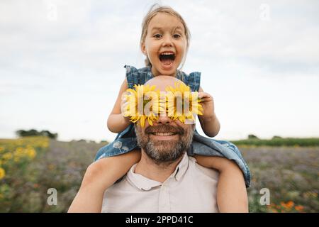 Sonnenblumen, die Augen der verspielten Mann mit Tochter in einem Feld Stockfoto