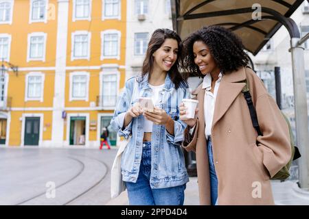 Glückliche Freunde, die mit dem Handy per Straßenbahn unterwegs sind Stockfoto