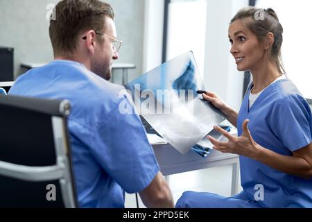 Ärztin, die über medizinisches Röntgen mit einer Kollegin diskutiert Stockfoto