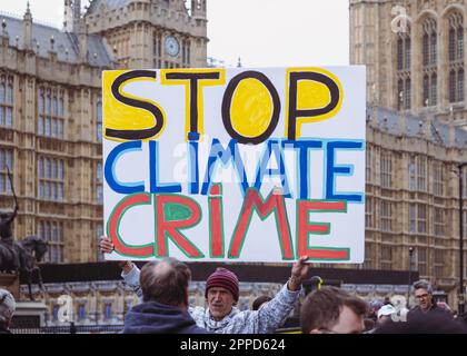 Man hält vor dem Palast von Westminster/Houses of Parliament ein großes Plakat mit dem Titel "Stop Climate Crime", Extinction Rebellion Protest, April 2023. Nach London. Stockfoto