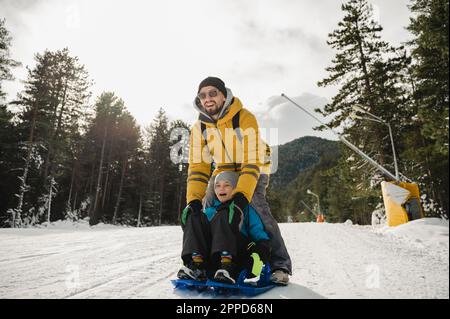 Glücklicher Vater und Sohn fahren gern auf Schnee Stockfoto