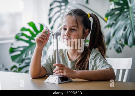 Mädchen mit rotierender Windturbine zu Hause Stockfoto