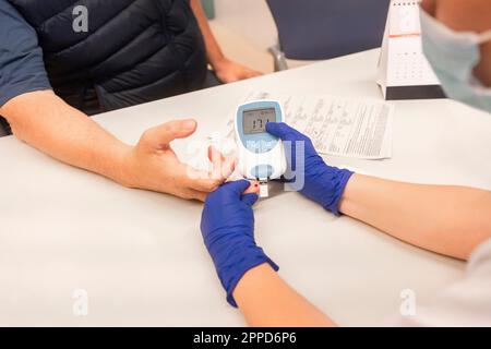 Arztprüfung des Blutzuckerspiegels des Patienten in der Klinik Stockfoto