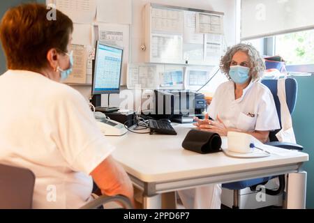 Arztbesprechung mit Seniorpatienten am Schreibtisch in der Klinik Stockfoto