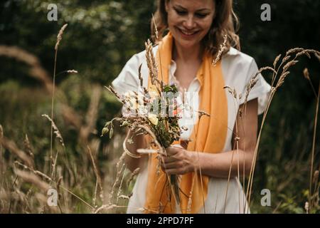Glückliche Frau mit einem Haufen Wildblumen auf dem Feld Stockfoto