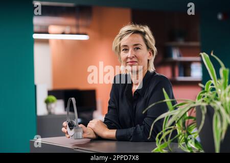 Lächelnde Geschäftsfrau mit VR-Brille im Büro Stockfoto