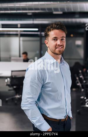 Lächelnder junger Geschäftsmann, der im Amt steht Stockfoto