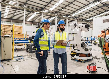 Ingenieure, die Schutzhelm tragen, um Maschinen in der Industrie zu untersuchen Stockfoto