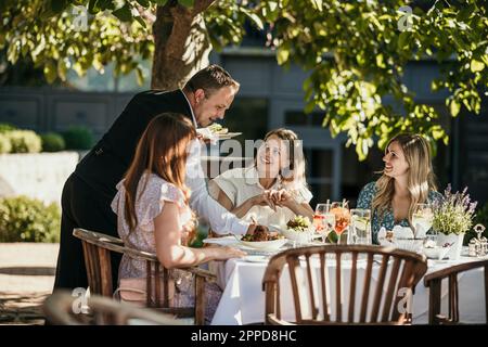 Der Kellner serviert den Frauen Essen im Restaurant Stockfoto