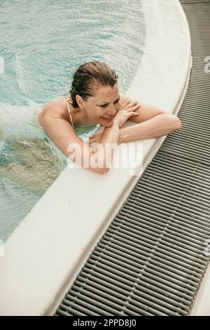Lächelnde, reife Frau, die sich im Pool amüsiert Stockfoto