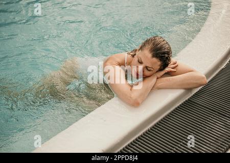 Frau mit geschlossenen Augen, die sich im Schwimmbad ruht Stockfoto