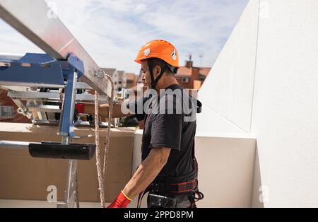 Ingenieur mit Schutzhelm steht an sonnigen Tagen an der Leiter Stockfoto