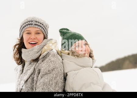 Glückliche Freunde, die Strickmützen tragen und den Schnee genießen Stockfoto
