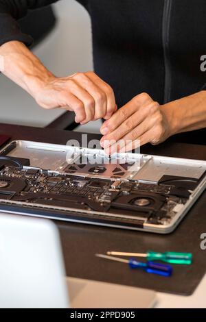 Die Hände eines Mannes reparieren den Laptop Stockfoto