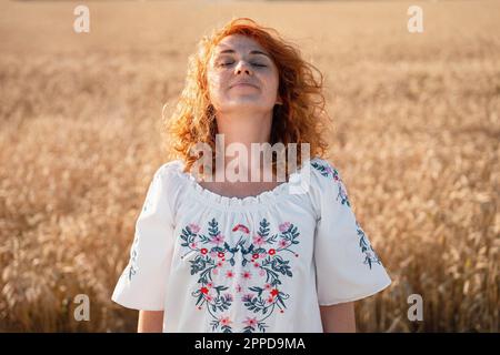 Lächelnde rothaarige Frau, die im Feld steht Stockfoto