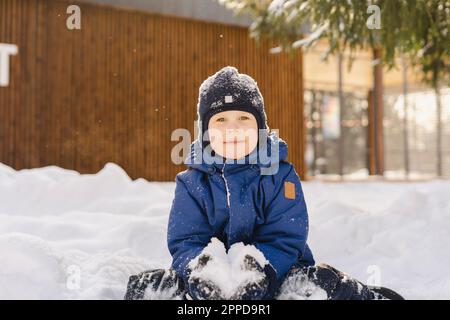 Süßer Junge mit Strickmütze und Schneeball Stockfoto