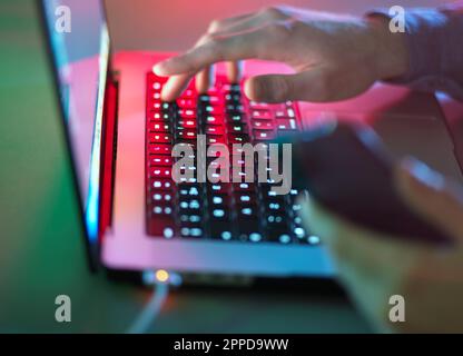 Hände, die im Büro im Dunkeln auf der Laptop-Tastatur tippen Stockfoto