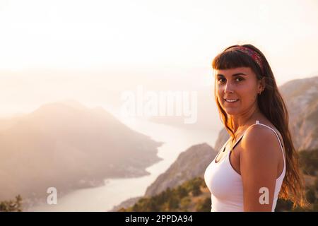 Lächelnde Frau, die vor den Bergen steht Stockfoto