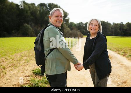 Glückliches, wanderndes Seniorenpaar, das Händchen in der Natur hält Stockfoto