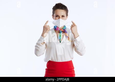 Moderne weibliche Stewardess vor weißem Hintergrund in Uniform mit FFP2 Maske. Stockfoto