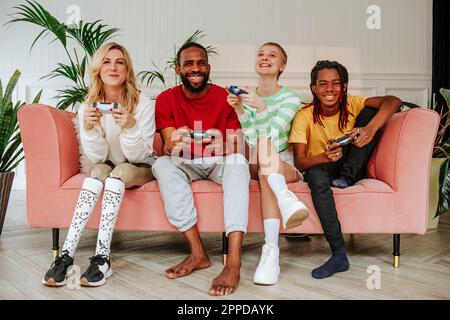 Vielfältige Freunde, die gemeinsam Spaß beim Spielen von Videospielen zu Hause haben Stockfoto