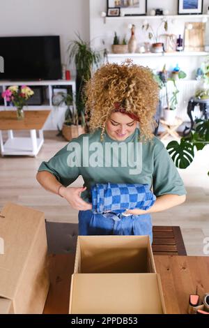 Junge Frau, Verpackungsreihenfolge in Pappschachtel zu Hause Stockfoto