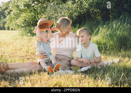 Glückliche Mutter, die mit Söhnen in der Natur sitzt Stockfoto