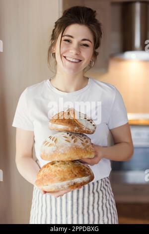 Lächelnde Frau mit frisch gebackenem Brot zu Hause Stockfoto
