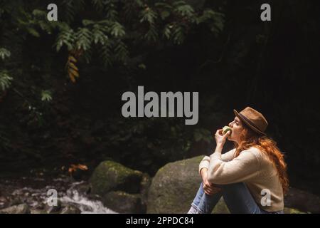 Junge Frau isst grünen Apfel im Wald Stockfoto