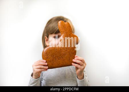 Mädchen mit Lebkuchen Osterhasen, das Gesicht vor weißem Hintergrund bedeckt Stockfoto