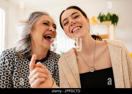 Glückliche reife Frau mit Tochter, die zu Hause Spaß hat Stockfoto