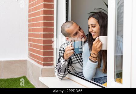 Glückliches Paar, das zu Hause Kaffee am Fenster trank Stockfoto