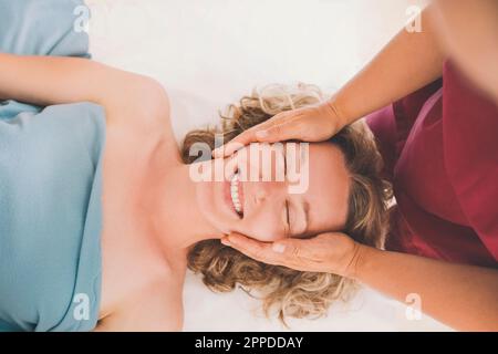 Therapeut gibt Kopfmassage an glücklichen Kunden im Salon Stockfoto