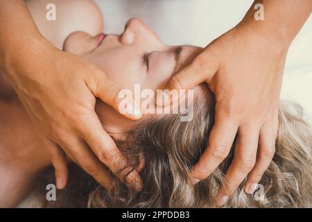 Hände des Therapeuten, der dem Kunden im Salon eine Kopfmassage gibt Stockfoto