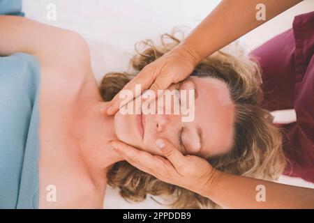 Therapeut, die dem Kunden eine Gesichtsmassage im Salon gibt Stockfoto