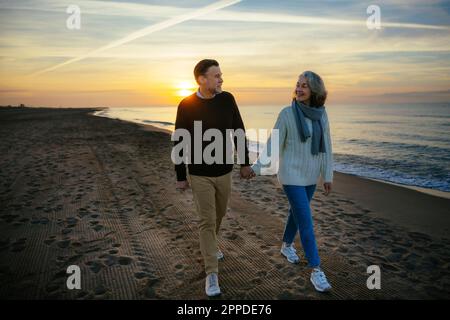 Lächelndes, reifes Paar, das am Strand spaziert Stockfoto