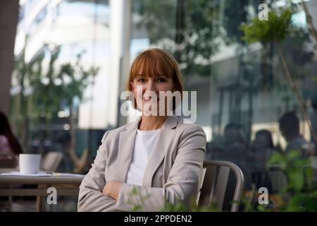 Selbstbewusste, reife Geschäftsfrau mit verschränkten Armen Stockfoto