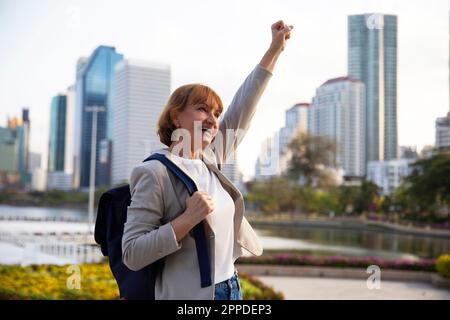 Fröhliche Geschäftsfrau mit geballter Faust, die die Hand hebt Stockfoto