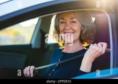 Glückliche reife Frau, die sich im Auto anschnallt Stockfoto