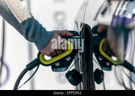 Hand eines Mannes, der ein Elektroauto auflädt Stockfoto