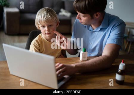 Vater zeigt dem Arzt die Windpocken seines Sohnes über einen Laptop zu Hause Stockfoto