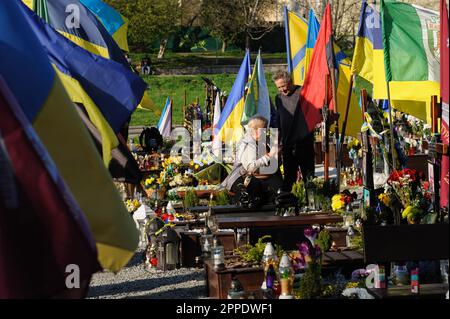 Lemberg, Ukraine. 23. April 2023. Ein älteres Paar, das am Grab eines geliebten Menschen auf dem Marsfeld auf dem Friedhof Lychakiv gesehen wurde. Die Menschen besuchen die gefallenen Helden der Ukraine, die das Territorium der Ukraine auf dem Friedhof Lychakiv verteidigten, wo sie begraben sind. Russland marschierte am 24. Februar 2022 in die Ukraine ein und löste damit den größten militärischen Angriff in Europa seit dem Zweiten Weltkrieg aus Kredit: SOPA Images Limited/Alamy Live News Stockfoto