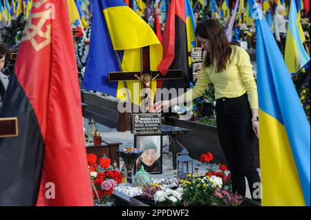 Lemberg, Ukraine. 23. April 2023. Eine Frau berührt ein Osterei am Grab eines geliebten Menschen auf dem Marsfeld auf dem Friedhof Lychakiv. Die Menschen besuchen die gefallenen Helden der Ukraine, die das Territorium der Ukraine auf dem Friedhof Lychakiv verteidigten, wo sie begraben sind. Russland marschierte am 24. Februar 2022 in die Ukraine ein und löste damit den größten militärischen Angriff in Europa seit dem Zweiten Weltkrieg aus Kredit: SOPA Images Limited/Alamy Live News Stockfoto