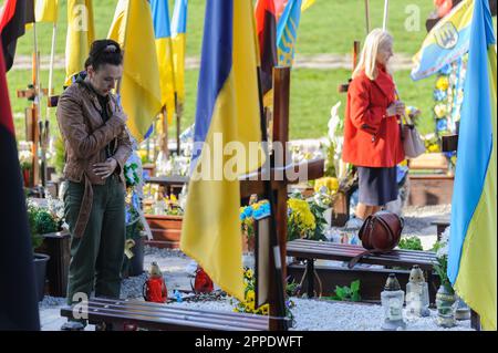 Lemberg, Ukraine. 23. April 2023. Frauen erweisen ihren Respekt an den Gräbern ihrer Lieben auf dem Marsfeld auf dem Friedhof Lychakiv. Die Menschen besuchen die gefallenen Helden der Ukraine, die das Territorium der Ukraine auf dem Friedhof Lychakiv verteidigten, wo sie begraben sind. Russland marschierte am 24. Februar 2022 in die Ukraine ein und löste damit den größten militärischen Angriff in Europa seit dem Zweiten Weltkrieg aus Kredit: SOPA Images Limited/Alamy Live News Stockfoto